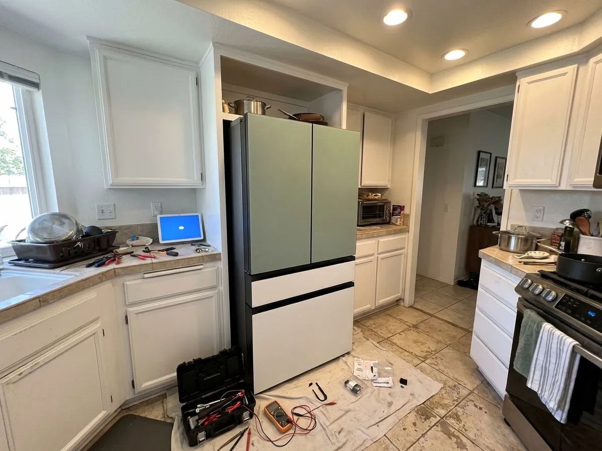 Four-door refrigerator with sage green glass upper doors and white lower drawers built into cabinets