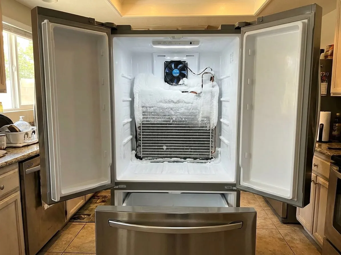 Freezer with the rear panel removed, the evaporator coil buried in a block of frost